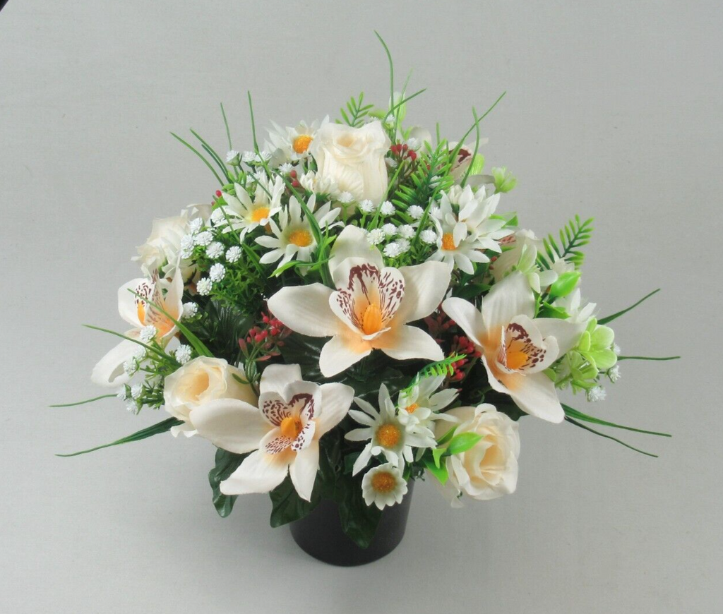 Artificial memorial arrangement with white lilies, roses, and orchids in a black cremation pot