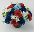 Memorial grave flower arrangement in dark pot with red, blue, white blooms and butterfly topper