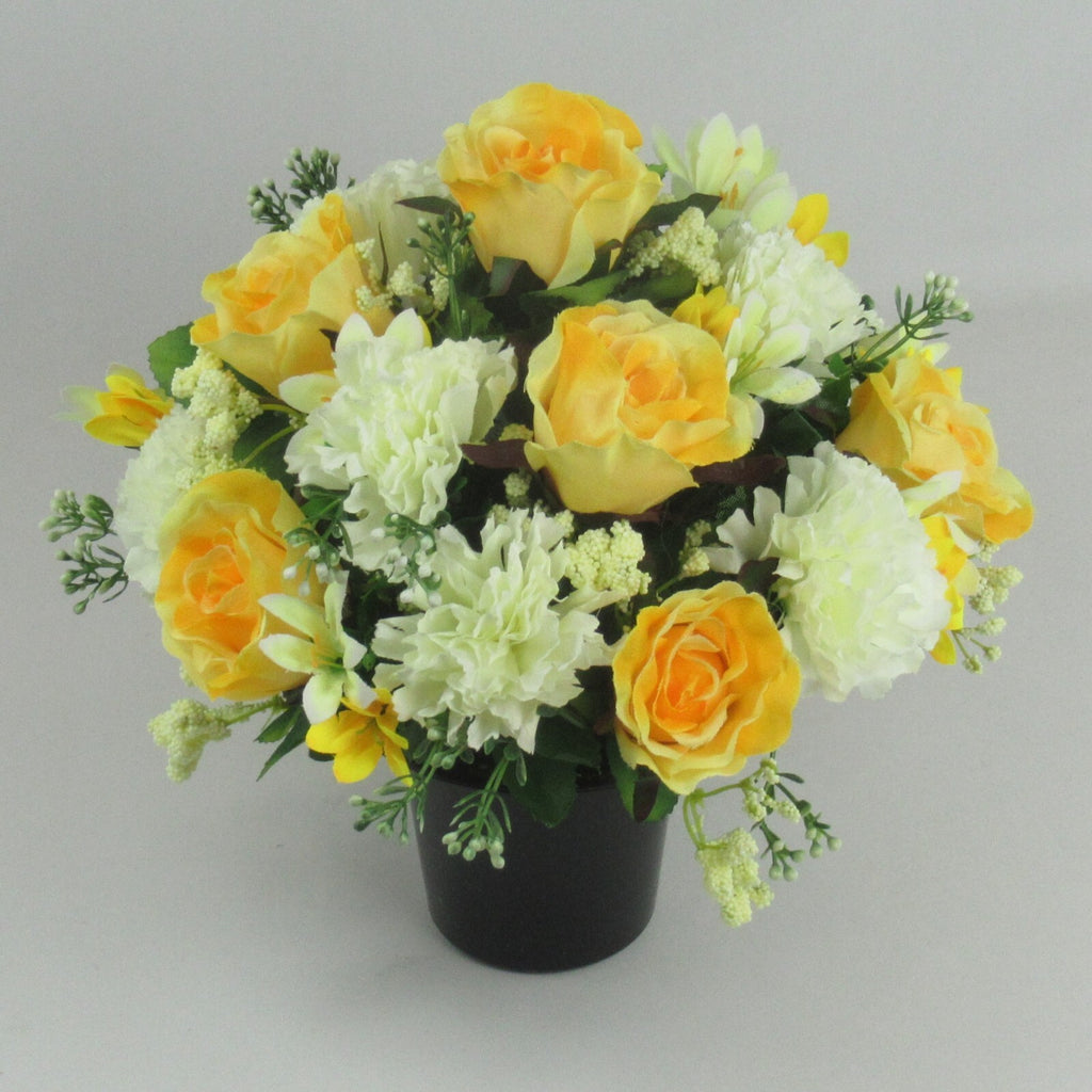 Artificial grave arrangement with yellow-orange roses and white carnations in dark pot