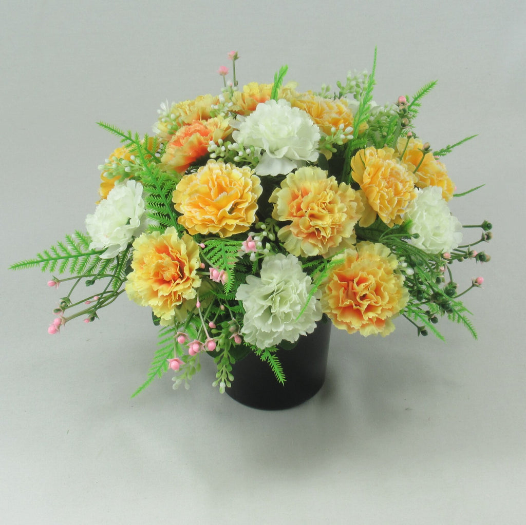 Black crem pot centerpiece with artificial flowers in yellow, orange, white and pink buds