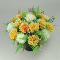 Artificial silk flower grave arrangement in black crem pot, orange, yellow, white blooms