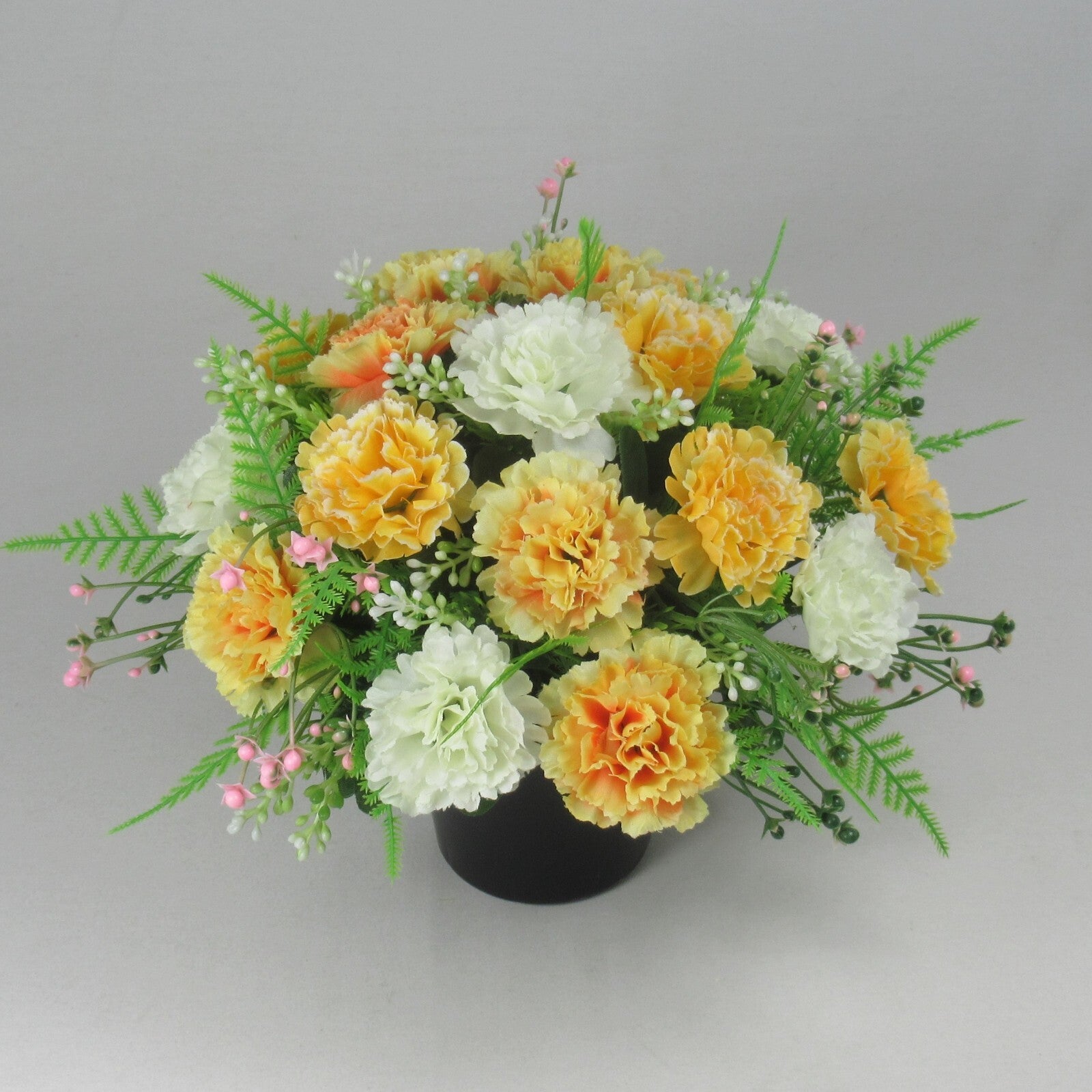 Front view artificial silk flowers in black crem pot, yellow, white and orange blooms