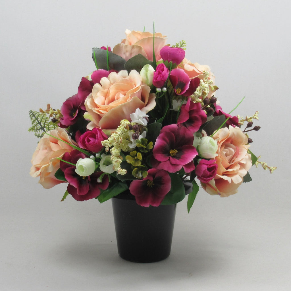 Artificial memorial bouquet in black pot with peach roses and deep magenta flowers