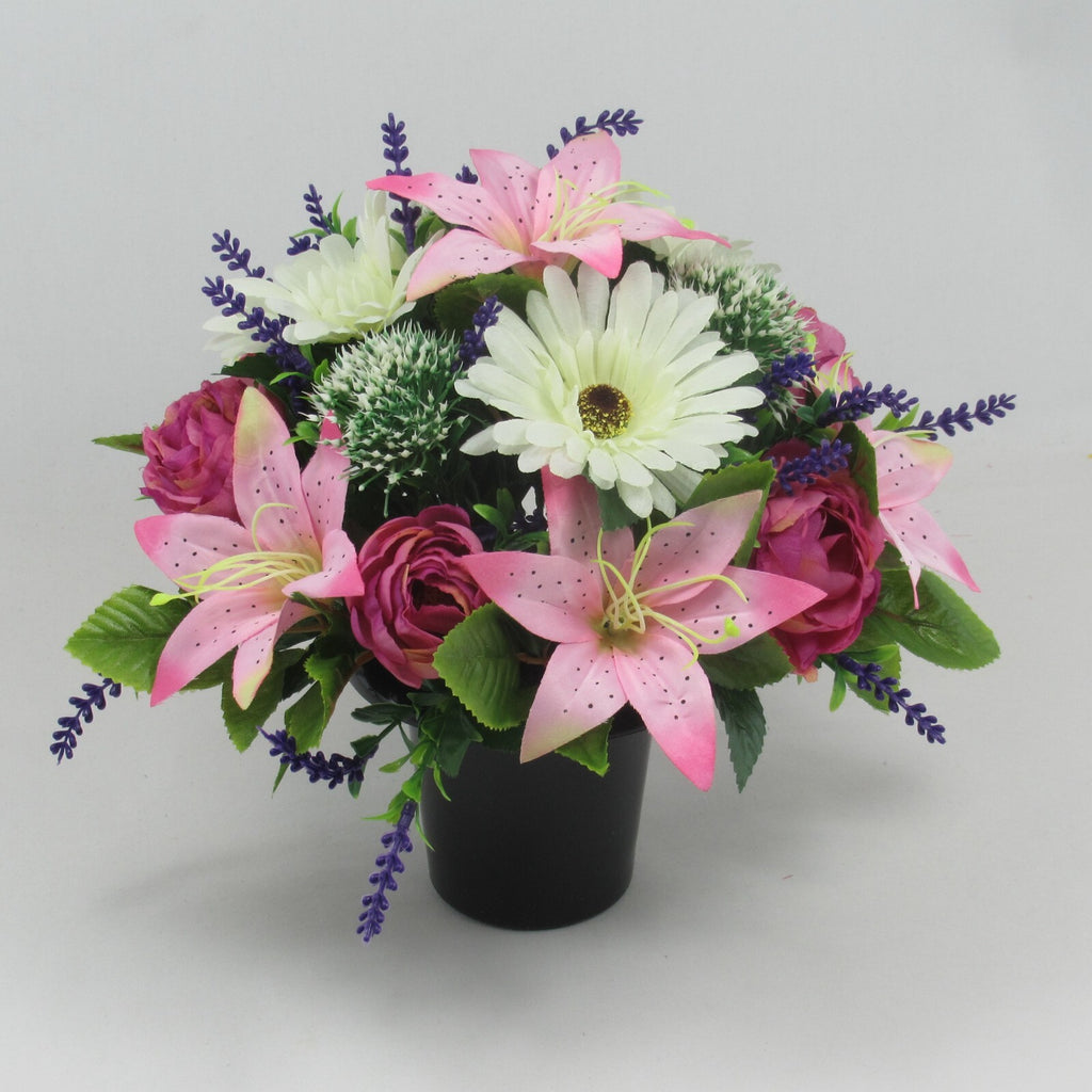 Memorial grave artificial pot with pink lilies, roses, white flowers, lavender sprigs.