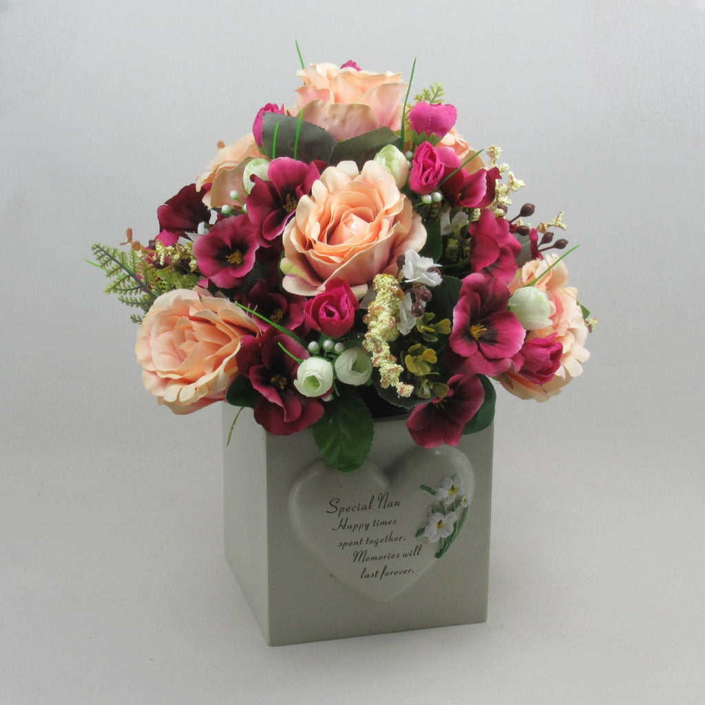 Artificial memorial flowers in gray planter with cream roses and magenta blossoms