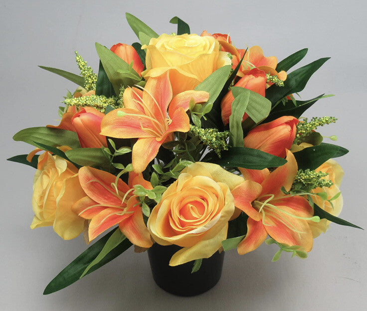 Artificial grave bouquet in black pot, yellow and orange open roses and lily with green leaves