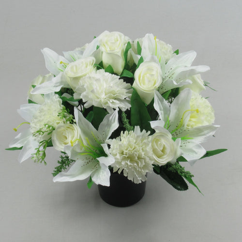 Artificial white flower arrangement in black memorial crem pot, lush green leaves