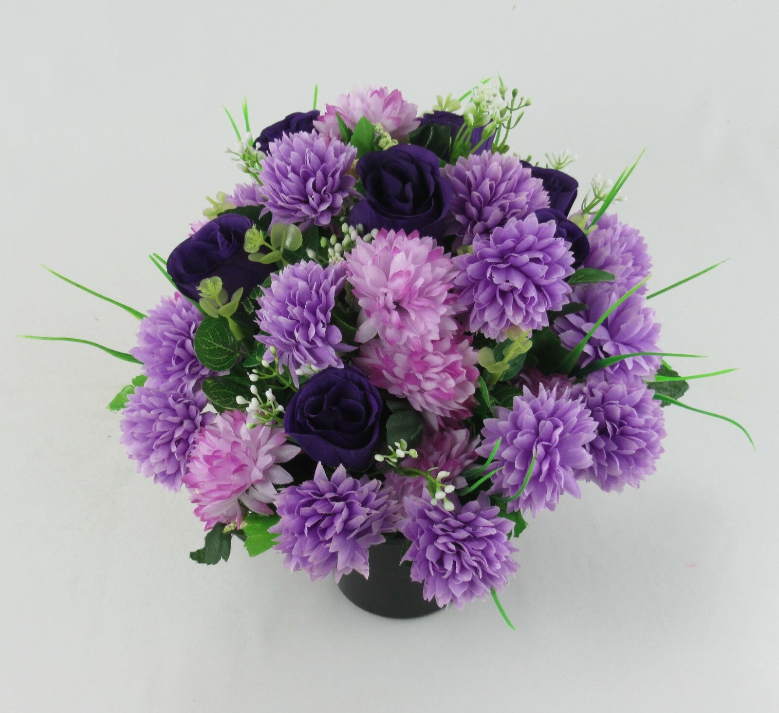 Purple artificial bouquet in dark pot for memorial, mix of lilac blossoms and navy rose blooms