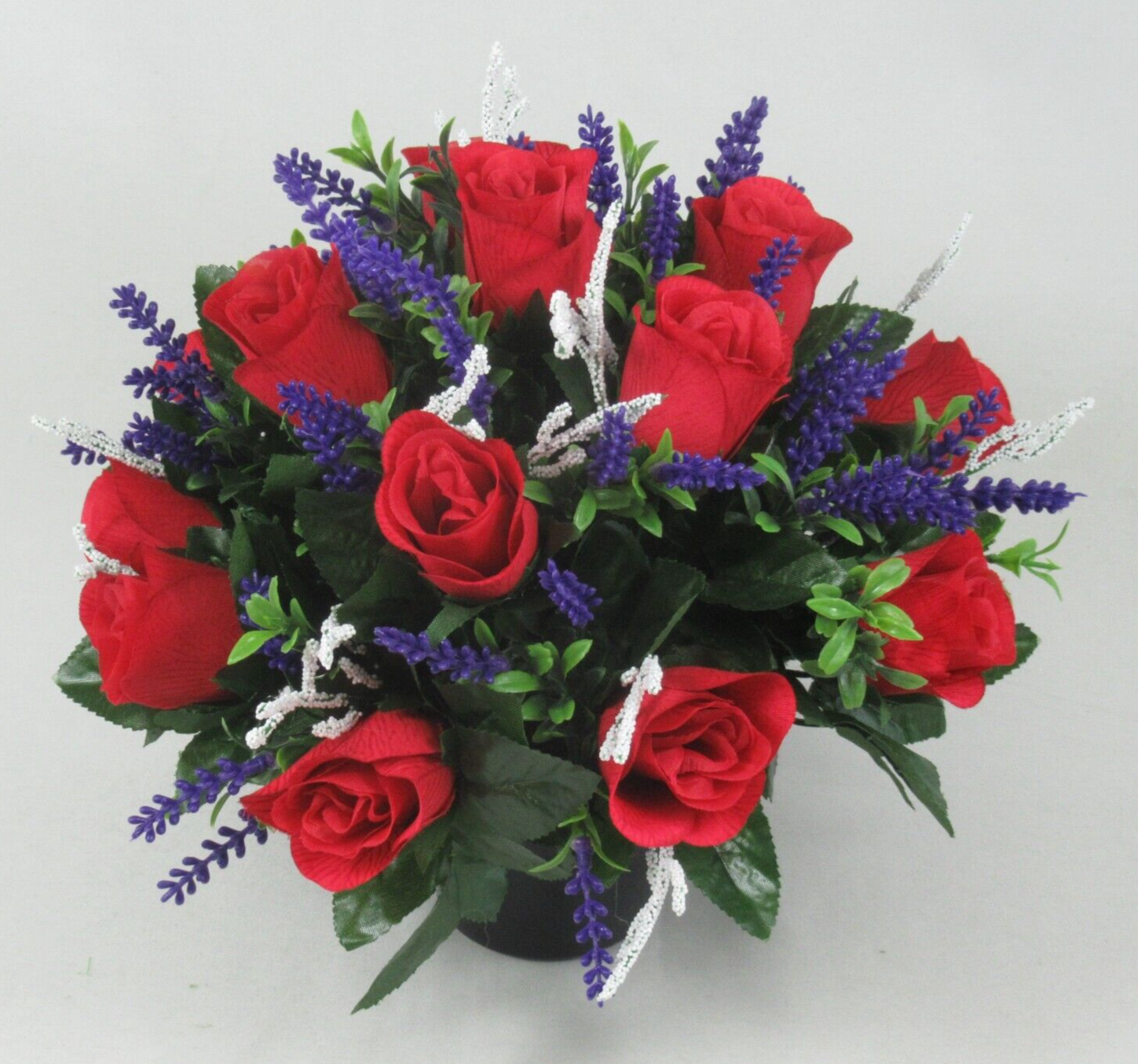 Close view memorial grave arrangement: red roses with purple spikes and silver-white ribbon stems