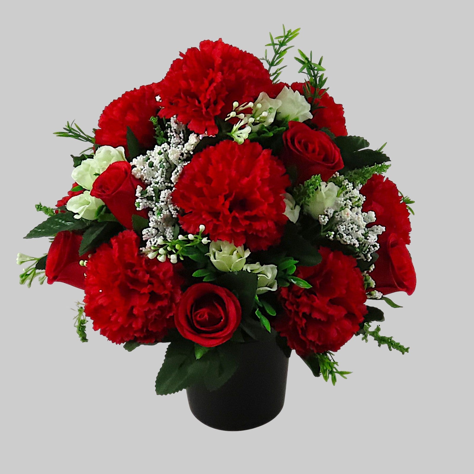 Artificial red rose and carnation grave flowers with white filler accents, black vase