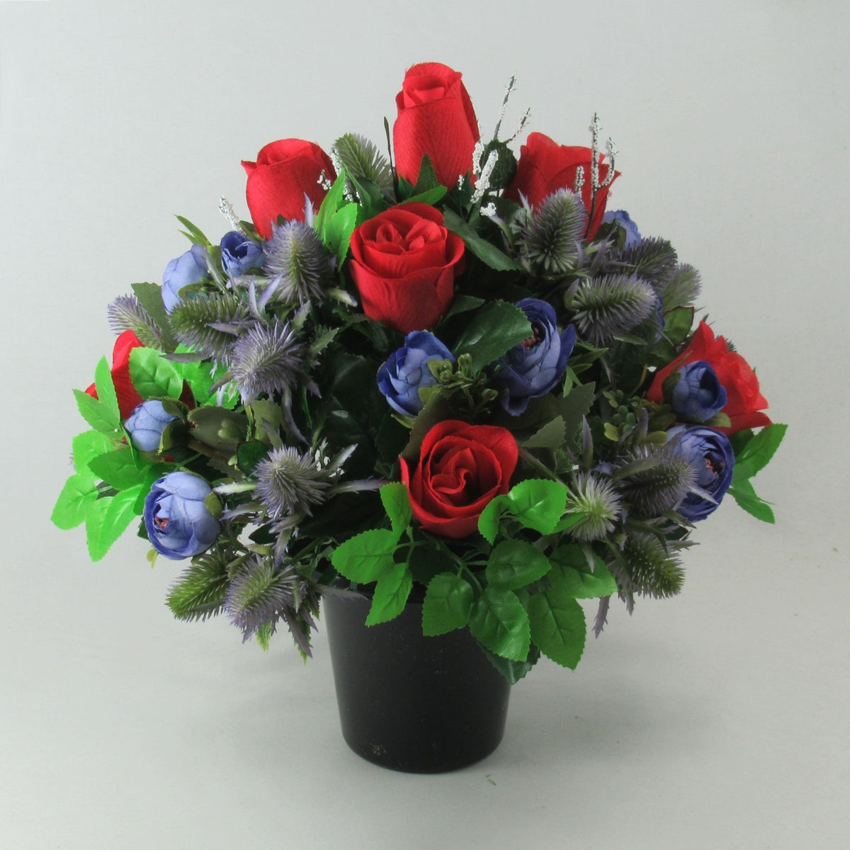 Artificial memorial bouquet: red roses and blue flowers with green leaves in black pot