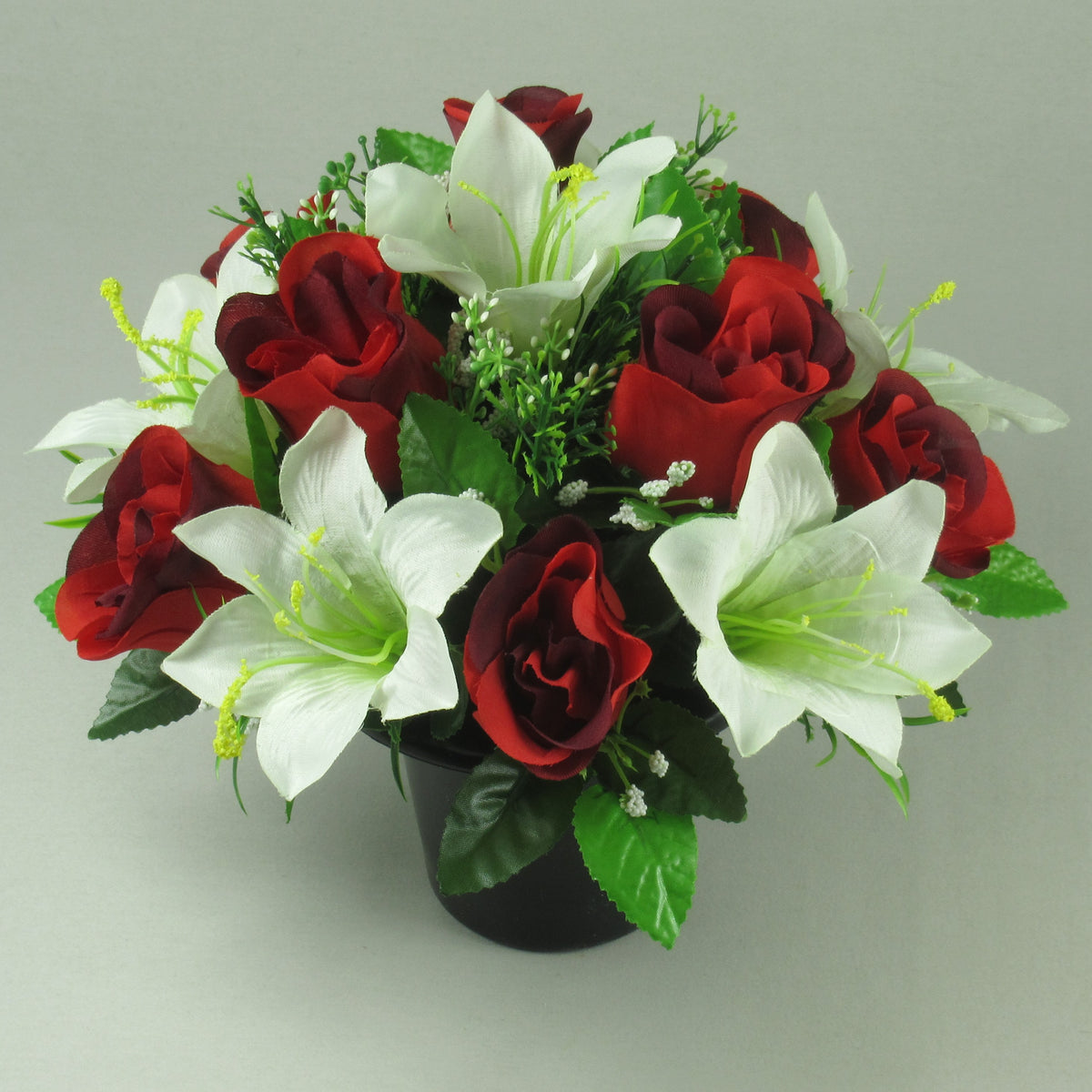 Artificial flower arrangement with red roses and ivory lilies in black memorial pot